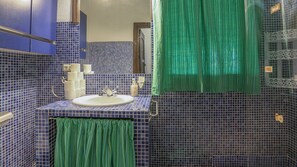 Un baño con lavabo, espejo y cortinas verdes.