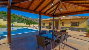 Un espace extérieur abrité comprenant une piscine, une table à manger et des chaises.