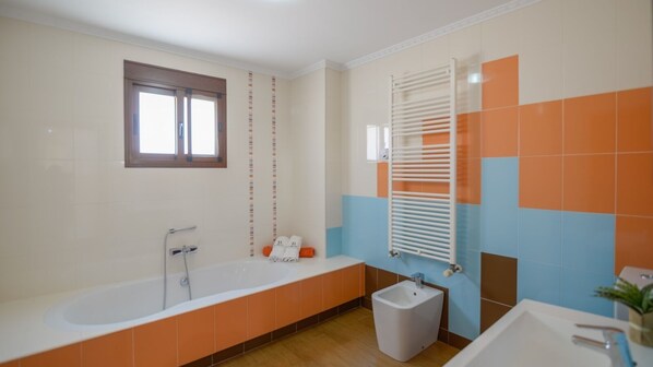 Une salle de bain avec une baignoire, un lavabo et un porte-serviettes.