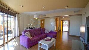 Un salon spacieux avec un canapé violet, une table basse et un téléviseur.