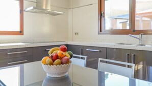 Une cuisine moderne avec une table en verre et un saladier rempli de fruits.