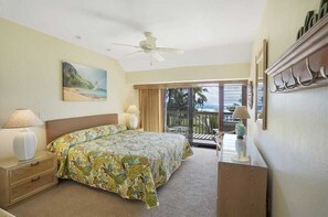 Ein Schlafzimmer mit einem Bett, Nachttischlampen, einem Deckenventilator, einem Gemälde und Blick ins Freie.