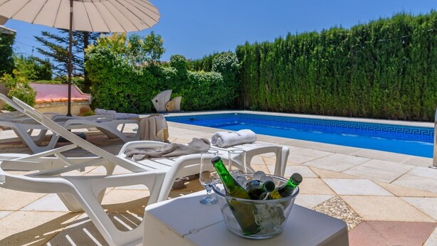 Area piscina con lettini, un tavolo con un secchio di bottiglie e vista diretta sulla piscina.