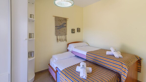 A small, cozy room with two beds, a shelf with toiletries, and a wall tapestry. - Villa del Mamut El Padul by Ruralidays (Granada)