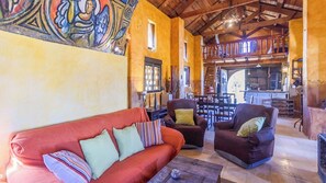 Una sala de estar acogedora con un sofá rojo, dos sillones, una mesa de centro y un comedor con muebles de madera.