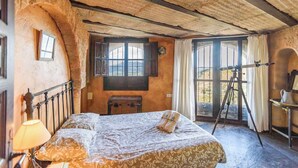 Ein rustikales Schlafzimmer mit einem Bett, einer Lampe, einem Fenster und einem Stativ.