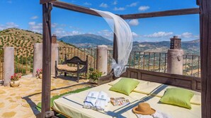 Ein Bett mit Bergblick, eine Sitzbank und ein weißes Tuch, das herunterhängt.