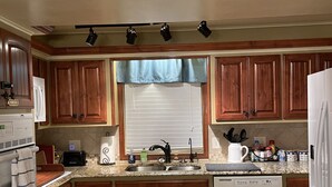 Una cocina con armarios de madera, un lavamanos doble, lavavajillas y una ventana con persianas.