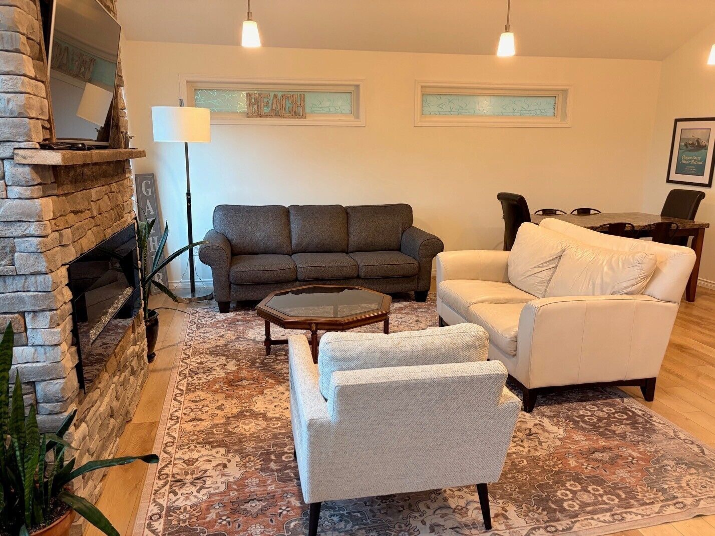 A living room with a stone fireplace, a sofa, a white armchair, a coffee table, and a rug.