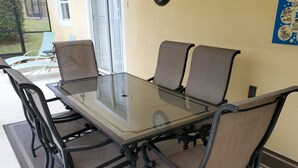 Ett bord med glasskiva och fyra stolar, där varje stol har en flätad sits och ett flätat ryggstöd.