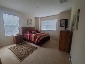 A bedroom with a bed, nightstand, dresser, and a rug. - Beautiful Vacation Home, Quiet Neighborhood, Sunny South Facing Pool (Davenport)