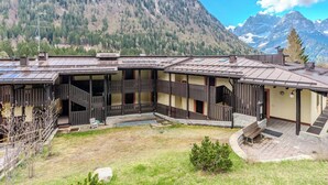 Een chalet met houten gevel, een overdekt terras en uitzicht op een bebost berglandschap.