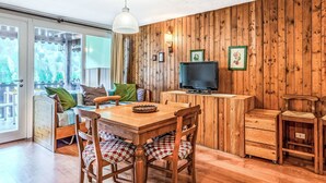 Een houten interieur met een eettafel, stoelen, een televisie en een schuifdeur naar een buitengebied.