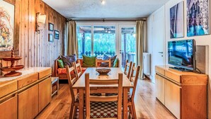 A wooden interior with a dining table, chairs, a TV, and a view of the outdoors. - Lovely apartment for 5 guests with WIFI, TV, balcony and pets allowed (Ragoli)