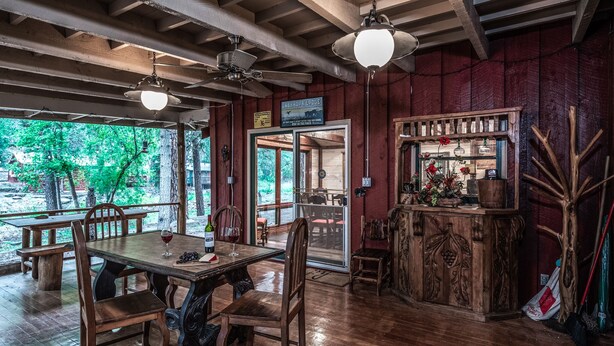 A rustic wooden dining area with a table, chairs, and a bar counter. - Cabin on Bear Creek (Ruidoso)