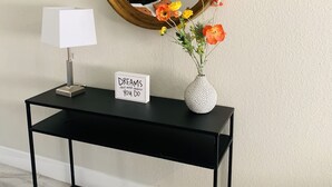 A black console table with a white lamp, a sign saying "DREAMS don't work unless YOU DO", and a white vase with flowers. - Private Studio, own entry, kitchenette,  full bath. (North Las Vegas)