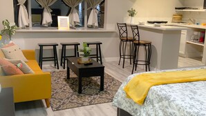 A modern living room with a sofa, coffee table, and a TV mounted above a window with curtains. - Private Studio, own entry, kitchenette,  full bath. (North Las Vegas)