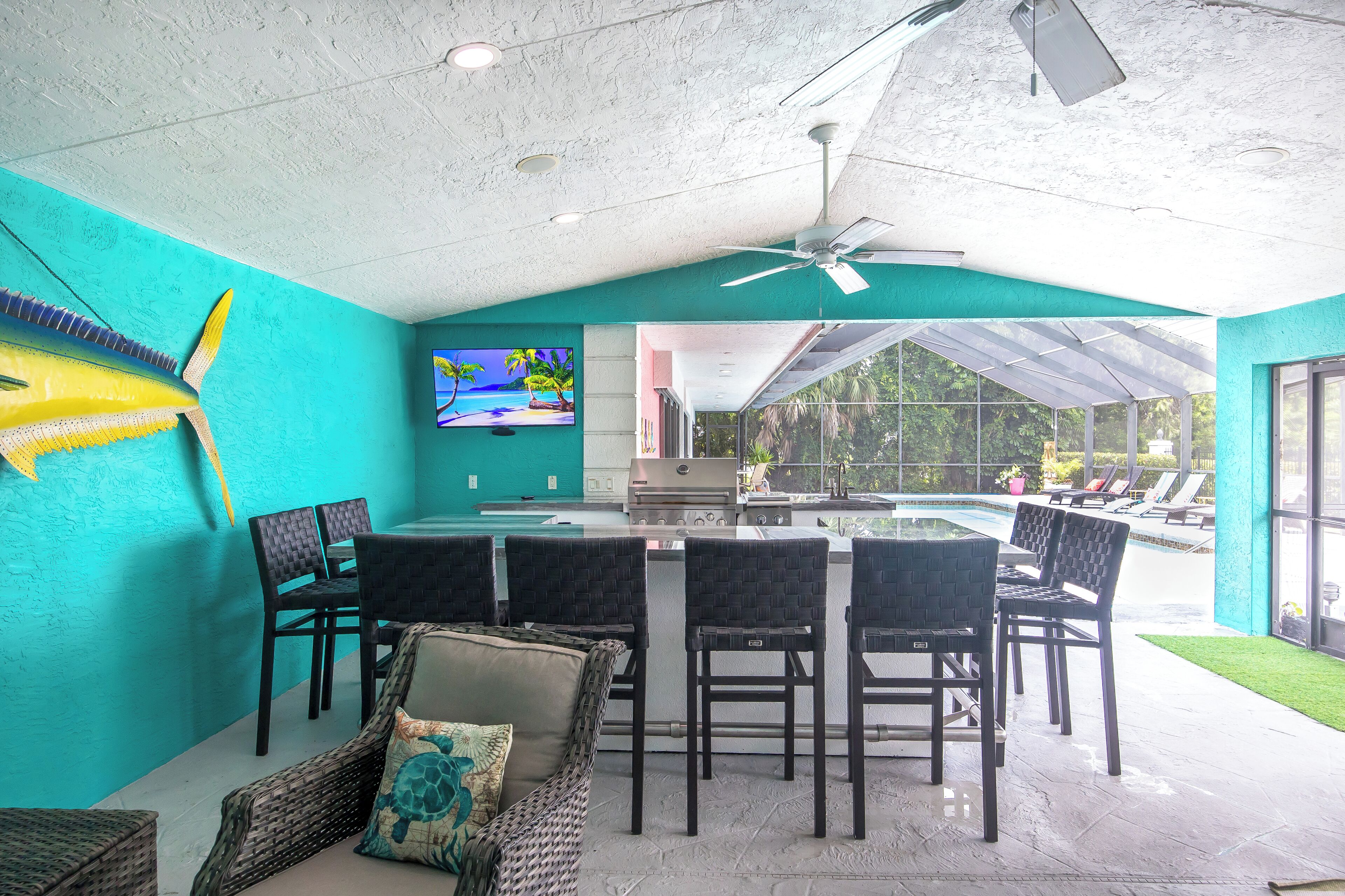 A covered outdoor area with a bar, seating, and a view of a swimming pool.
