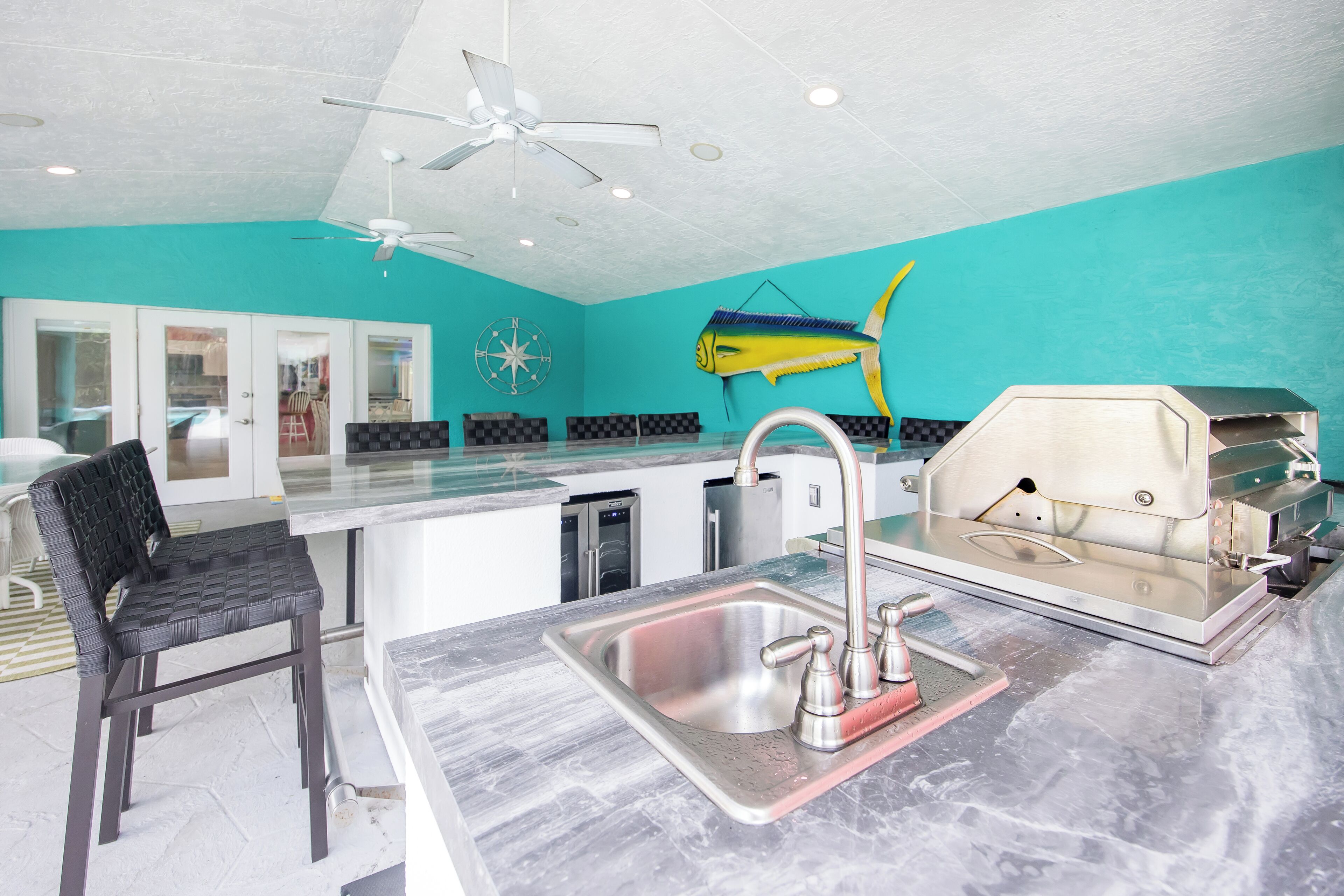A kitchen with a sink, a grill, a ceiling fan, and a fish wall decoration.