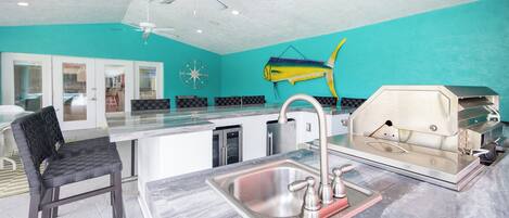 A kitchen with a sink, a grill, a ceiling fan, and a fish wall decoration.