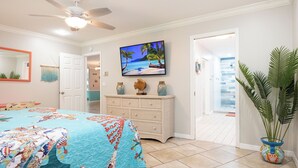 A bedroom with a bed, a dresser, a television, and a potted plant. - Palm Palace - 2 House Compound Sleeps Up to 22!  Huge Pool and near the beaches (Fort Myers)