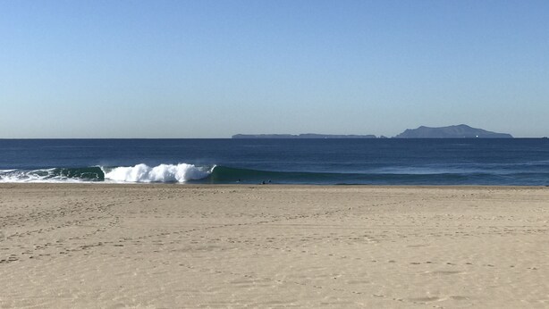 A beach with waves, a clear sky, and distant mountains. - ON THE SAND! (Oxnard)