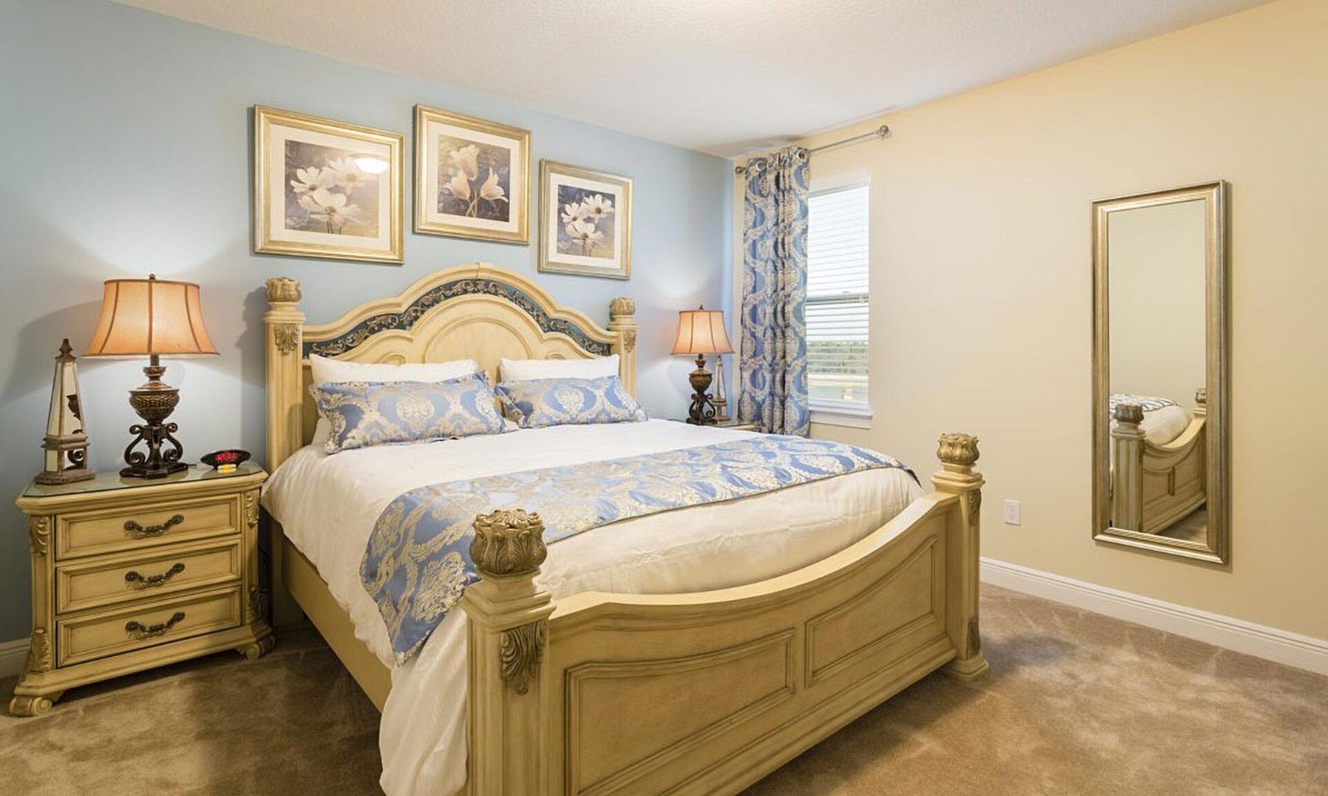 Quarto com cama, duas mesas de cabeceira, cômoda, espelho e três quadros na parede.