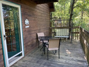 Enjoy the serene forest views from the cabin's spacious deck, featuring a comfortable seating area with a table and chairs.