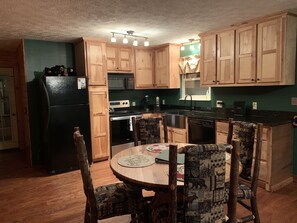Compact kitchen with central island and seating, featuring a refrigerator, microwave, stove, and dishwasher.