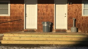A wooden house with two white doors, numbered 1 and 2, and a small trash can in front. - Home Away From Home, Newly Renovated Apartment (North Troy)