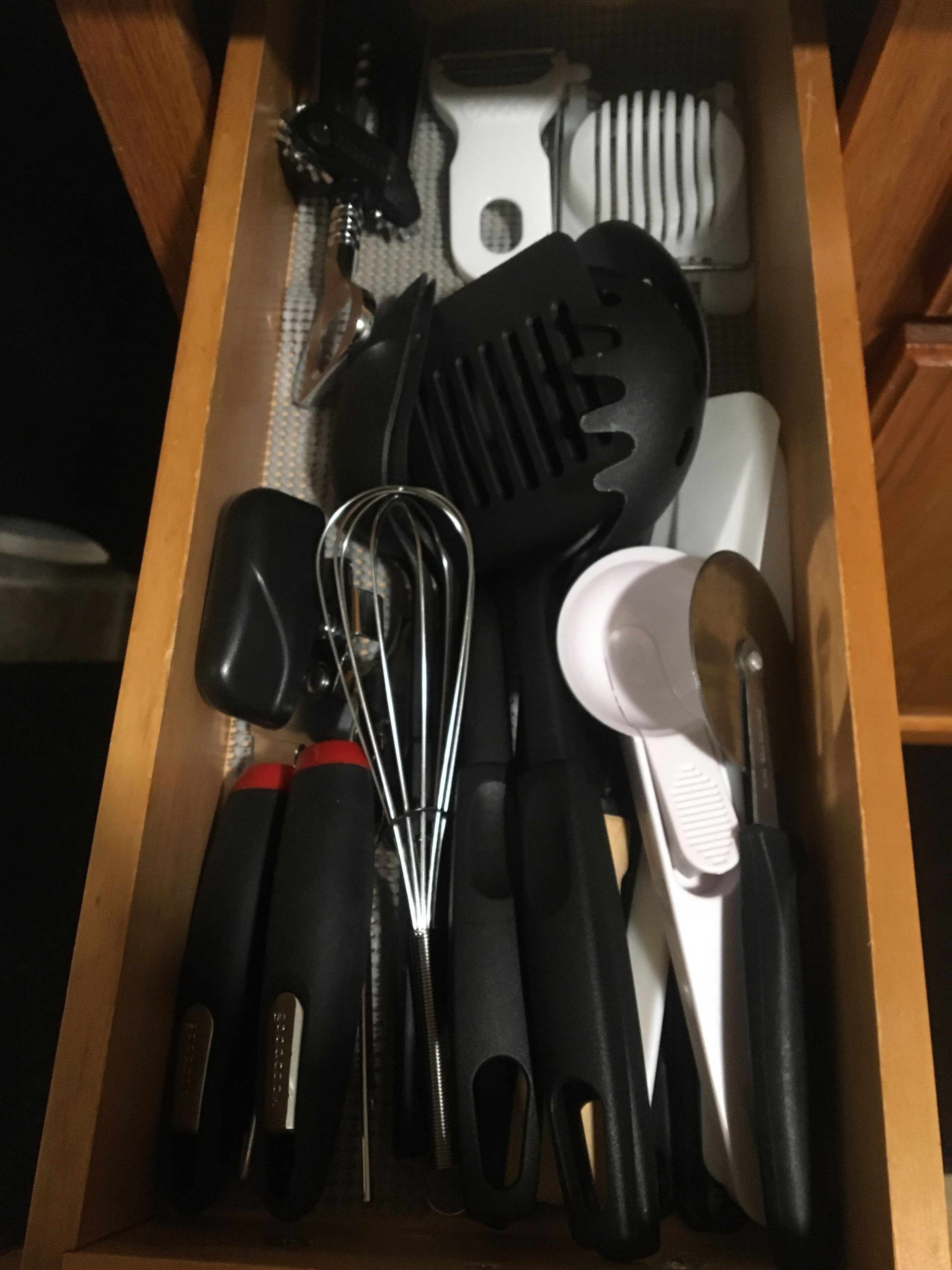 A drawer containing various kitchen utensils including a whisk, spatula, and a grater.