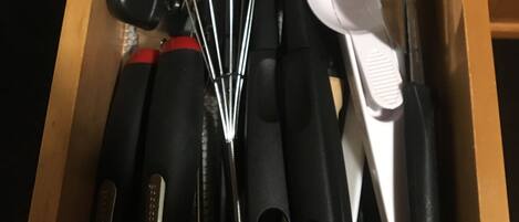 A drawer containing various kitchen utensils including a whisk, spatula, and a grater.