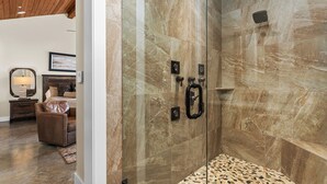 Une salle de bain moderne avec une douche à parois de verre, des murs en marbre et un sol à motifs.