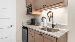Una cocina equipada con microondas, cafetera y dispensador de toallas de papel.