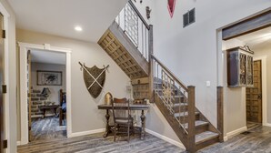 Una escalera de madera con barandilla de metal que conduce a una habitación con una mesa y sillas de comedor.