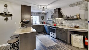 Una cocina moderna con armarios oscuros, una isla central y una lámpara colgante.