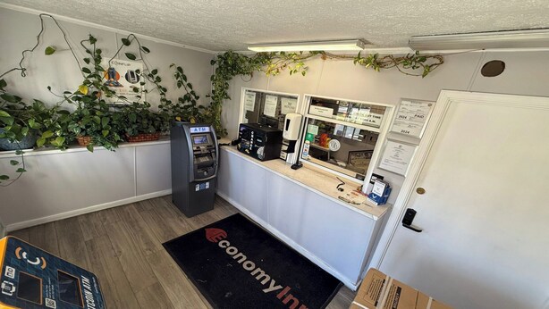 Habitació amb taulell de recepció, un caixer automàtic, una porta i un estri de fregar amb el logotip 'Economy Inn'.