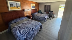 Habitació d'hotel amb dos llits, un escriptori, una cadira i una finestra amb cortines.
