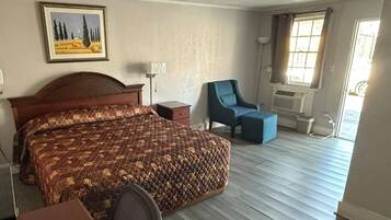 Een hotelkamer met een groot bed, een stoel, een bureau en een raam met gordijnen.