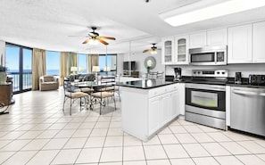 Enjoy meals in the kitchen with a central island, integrated appliances, and ample counter space, complemented by a dining area with a round table and comfortable seating.