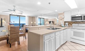 A modern kitchen with a central island, white cabinetry, and a view of the ocean.