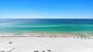 A beach with a row of umbrellas and a sandy shore. - High-Floor 1BR Condo With Gulf Views, Balcony and Sleeps 4 (Destin)