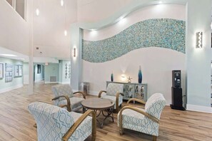 A spacious lobby with a curved wall mosaic, a round table with chairs, and a cash machine. - High-Floor 1BR Condo With Gulf Views, Balcony and Sleeps 4 (Destin)
