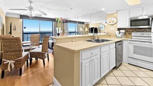 A modern kitchen with white cabinets, a large island with a sink, and a view of the ocean. - High-Floor 1BR Condo With Gulf Views, Balcony and Sleeps 4 (Destin)