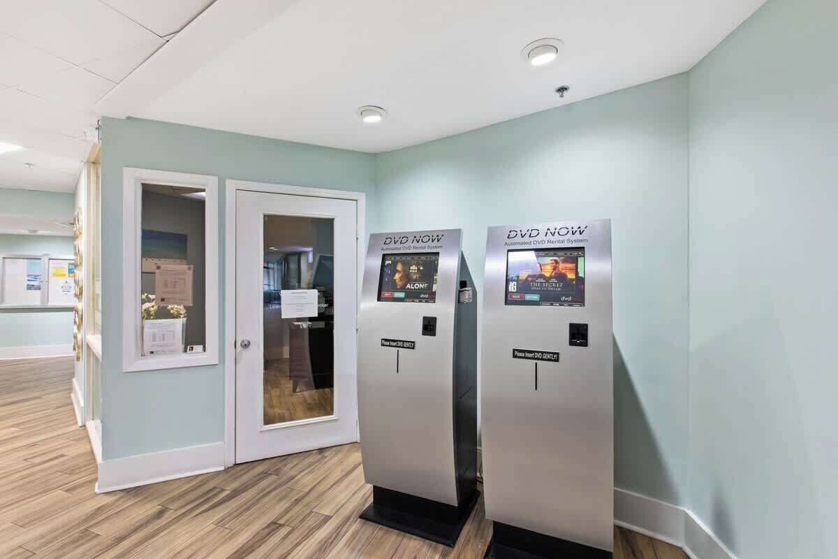 A hallway with two automated DVD rental kiosks and a door leading to a room.