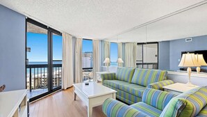 A modern living room with a sofa, coffee table, and a view of the beach. - SunDestin Resort Unit 1117 (Destin)