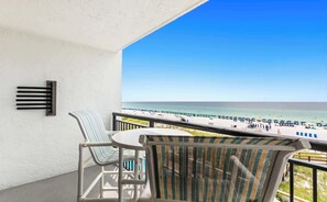 A balcony with a view of a beach, a table, and two chairs. - SunDestin 1BR Gulf-Front Condo With Cheerful Coastal Charm - Unit 0407 (Destin)