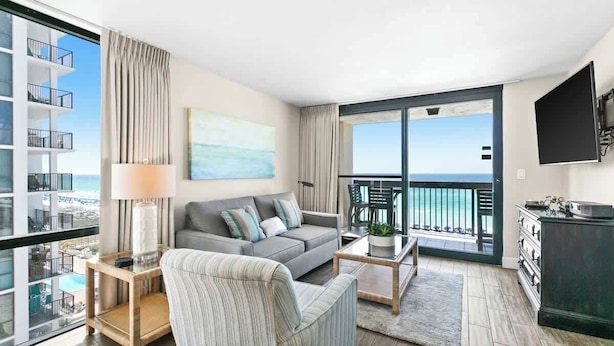 A modern living room with a sofa, coffee table, and a view of the ocean through large windows. - SunDestin 2BR Condo With Panoramic Gulf Views and Sleeps 7 - Unit 0601 (Destin)