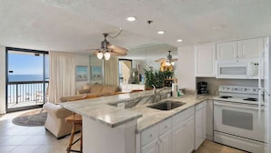 A modern kitchen with a large island, white cabinetry, and a view to the outside.