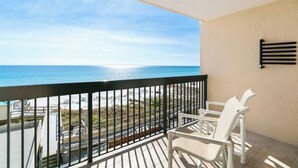 A balcony with a view of the beach and ocean.